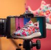 A pair of sneakers with a camera and a pair of shoes on it (shoe photography)