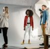 People working in a photo studio with a white backdrop and a camera