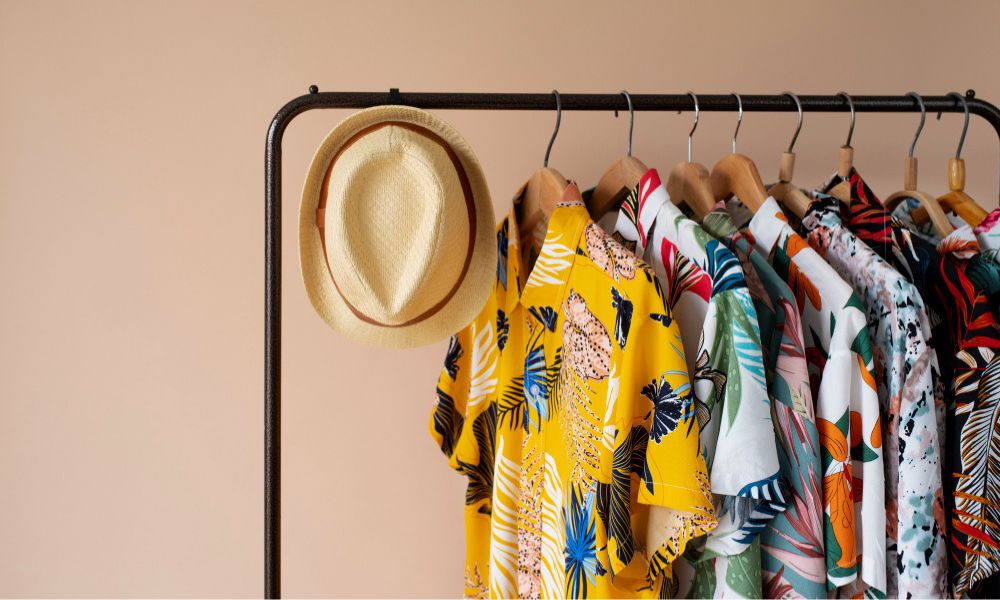 Clothing rack with floral hawaiian shirts on hangers and hat