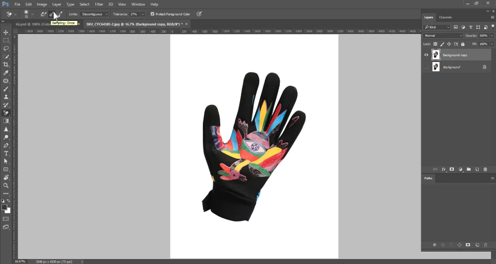 A Photoshop screenshot displays a black cycling glove with a vibrant, colorful design on the palm, against a white background. The cursor is hovering over the "Sampling: Once" option in the top toolbar, which is part of the Background Eraser Tool settings. The layers panel on the right shows "Background copy" and "Background" layers.