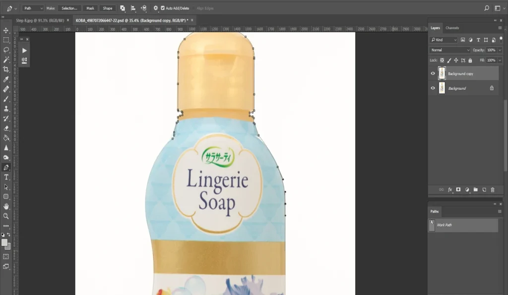 A screenshot of Adobe Photoshop shows a bottle of "Lingerie Soap" with a floral design, zoomed in to 91.3% and outlined with a path tool against a white background