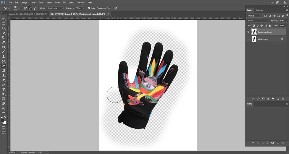 A Photoshop screenshot shows a black cycling glove with a colorful design on the palm, partially isolated on a transparent background indicated by a checkerboard pattern. A circular brush cursor, characteristic of the Background Eraser Tool, is positioned near the wrist area of the glove, suggesting the background is being actively removed. The layers panel on the right displays "Background copy" and "Background" layers