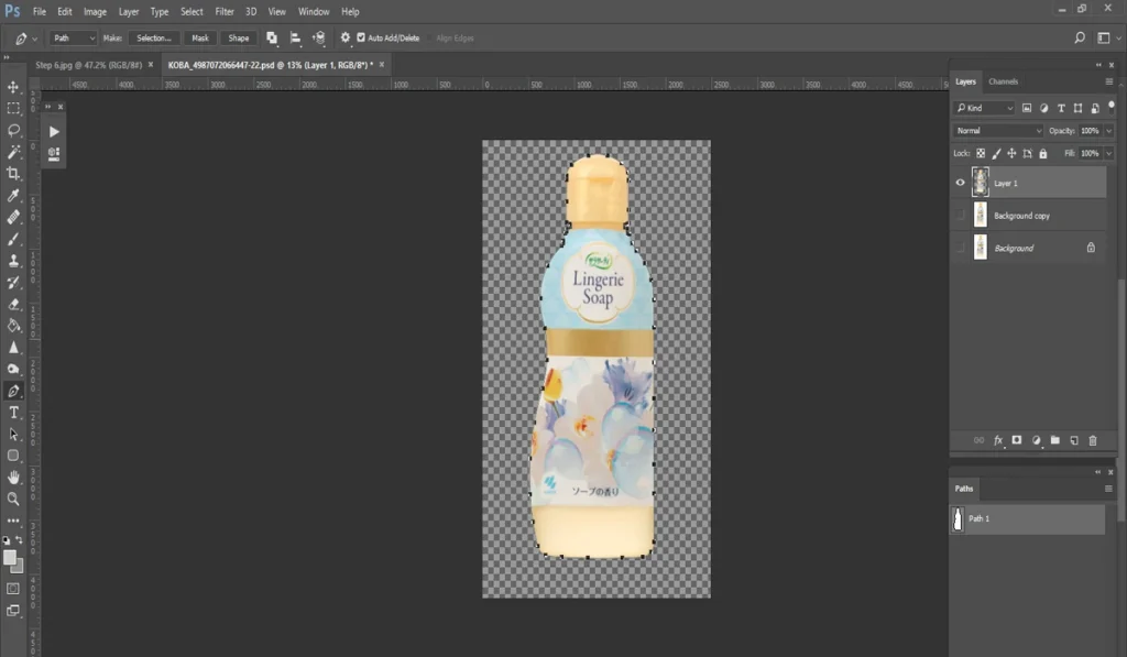 A screenshot of Adobe Photoshop displays a bottle of "Lingerie Soap" with a floral pattern, isolated on a checkered transparent background, ready for further editing