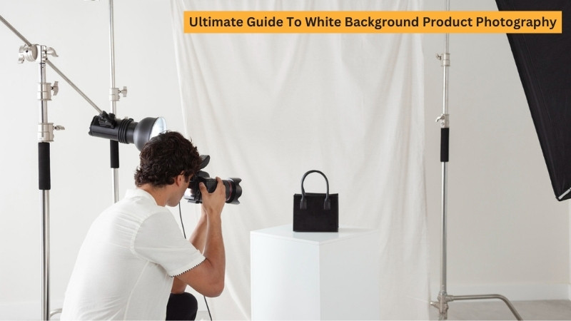 Photographer shooting a black handbag on a white cube in a studio with white backdrop and lights