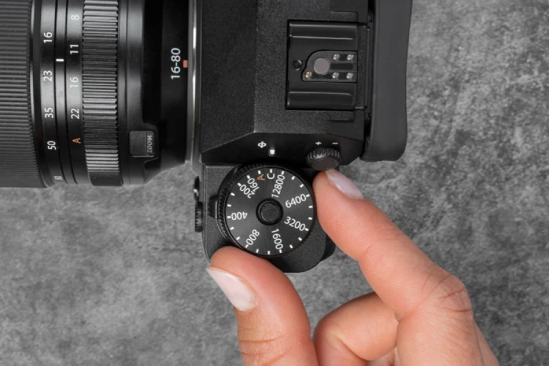 close-up of a person adjusting the ISO dial on a digital camera