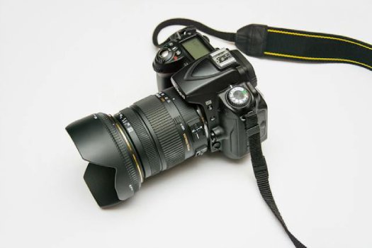 Digital SLR camera with a zoom lens and strap, placed on a white background