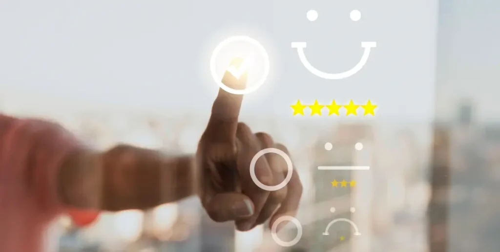 A human finger with a glowing circle around its tip presses on an illuminated smiley face icon, part of a set of feedback emojis ranging from happy to sad, with five yellow stars for rating, all against a blurred background