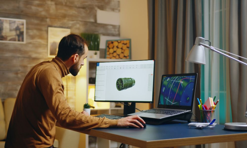 Man working on a 3D product design using dual monitors in a home office setup with modern decor