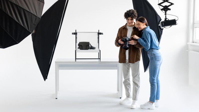 Photographers capturing packshot images of a handbag under studio lights.