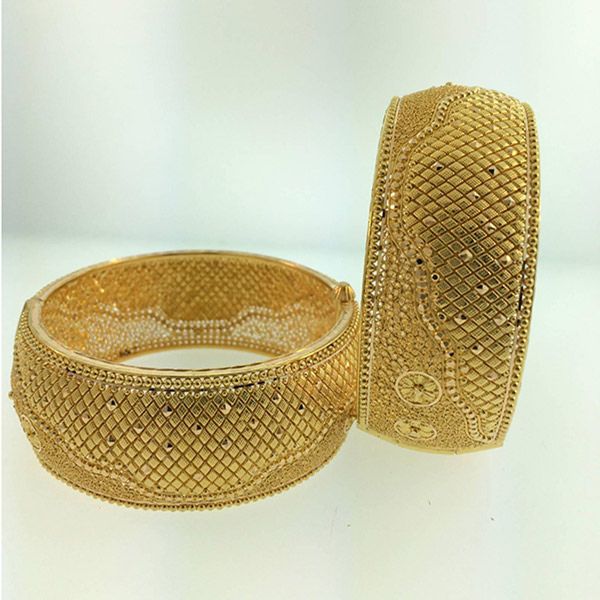 Two heavily textured gold bangles, one slightly open, are displayed against a soft, bright background