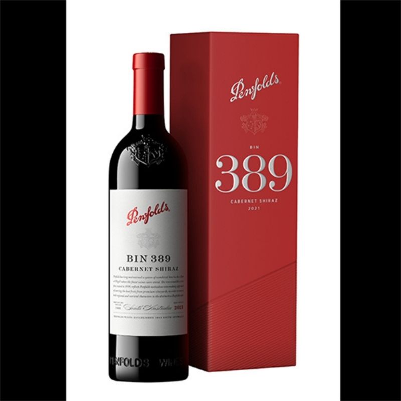 A dark bottle of Penfolds Bin 389 Cabernet Shiraz wine with a red foil top and white label, standing next to a tall red gift box for the wine. The background is black with white borders on the sides