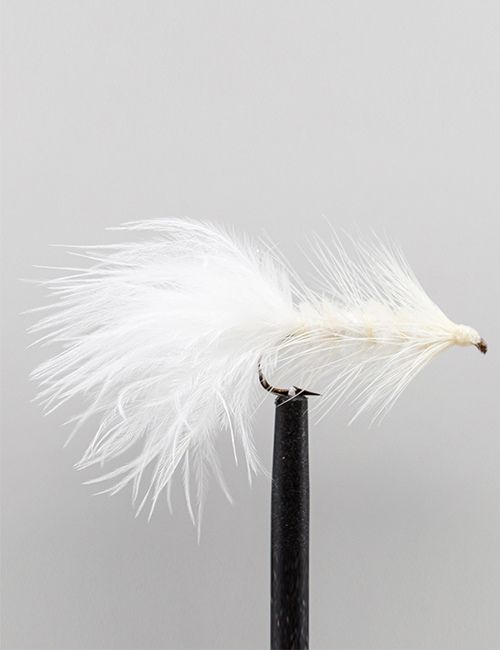 A detailed close-up of a white feathered fly fishing lure with a barbed hook, held upright by a black tool against a plain grey background