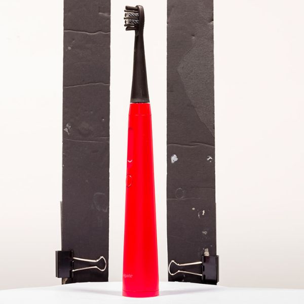 Red and black electric toothbrush between black paper strips on white