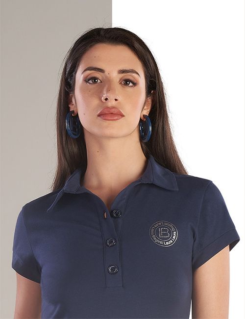 A dark-haired woman wearing a navy blue polo shirt with a silver logo and large blue hoop earrings. The image is split, with the left side having a grey background and the right a white background (comparing a model before and after