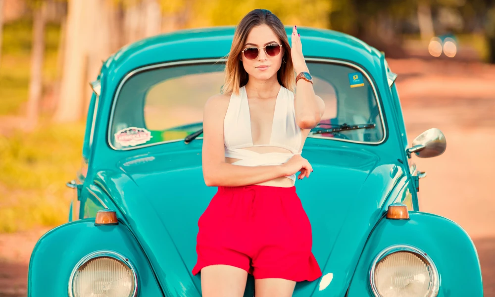 A young woman poses with vintage car